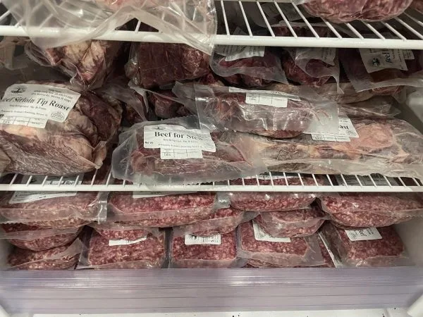 Quarter beef in the freezer, labeled by cut Freezer shelves at Nadig Farms holding a quarter beef in vacuum-sealed packages labeled by cut, including sirloin tip roast, beef for stew, and ground beef