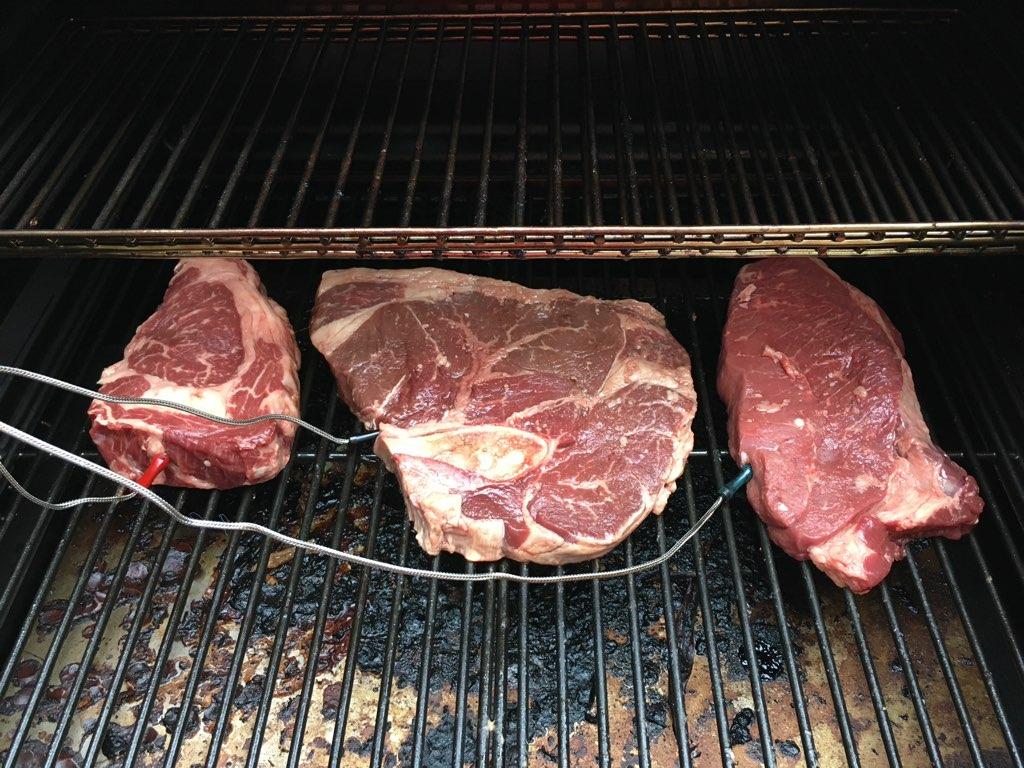 Three Nadig Farms steaks searing on a grill.