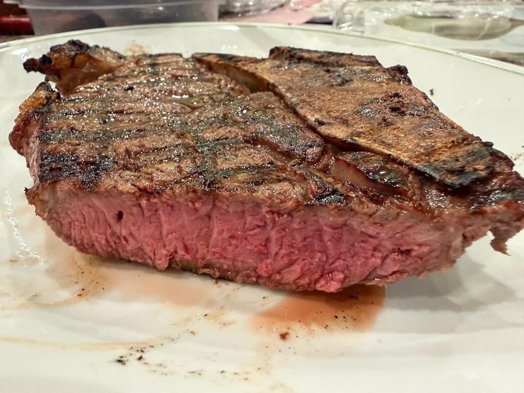 Grilled T-bone steak cooked rare, plated and resting, from Nadig Farms grain-finished Angus beef.